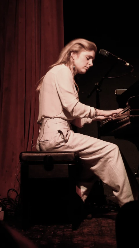 a woman playing a piano in a dark stage