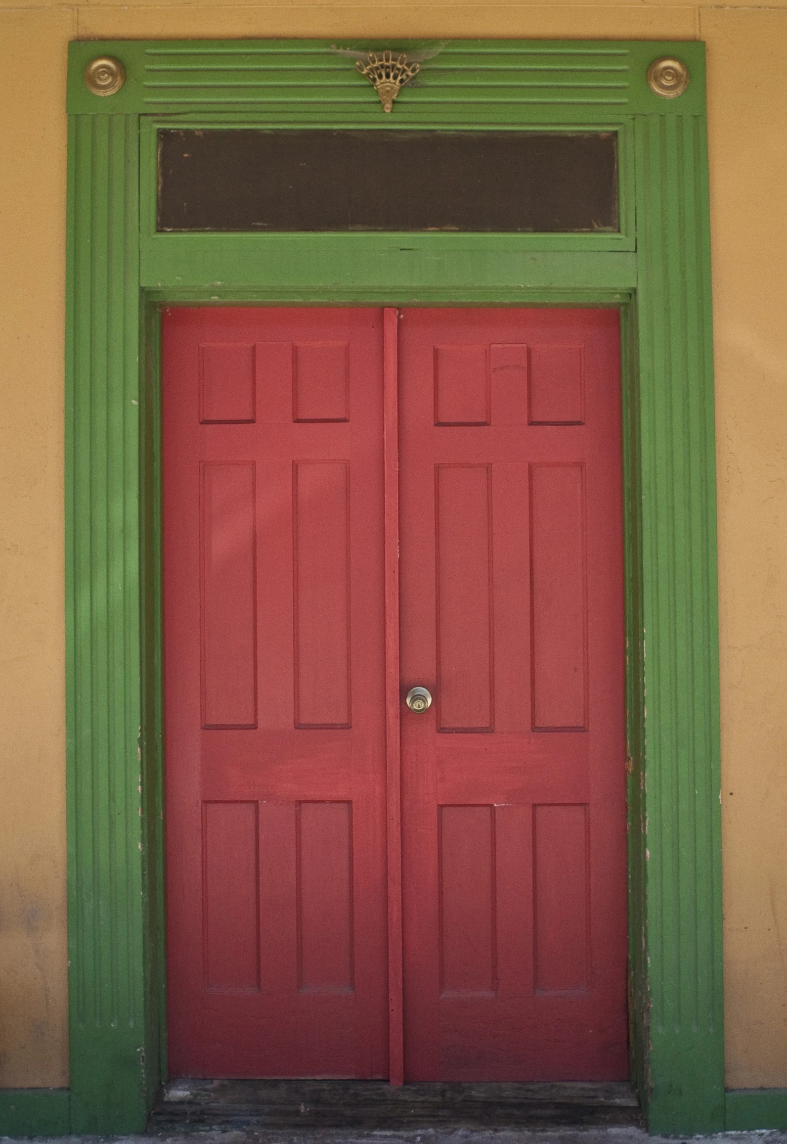 an old yellow building with a large red door