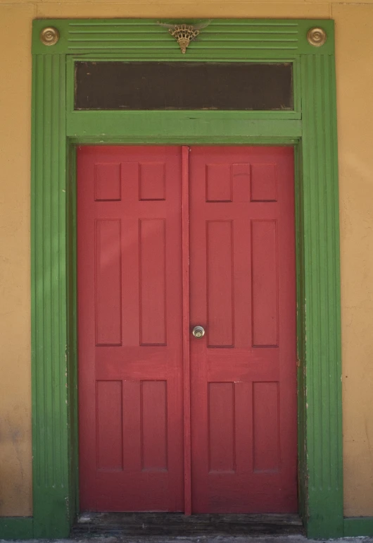 an old yellow building with a large red door