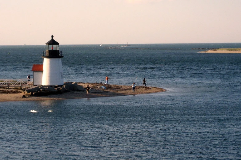 people are standing on an island with the lighthouse in the background