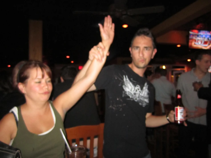 two people in a bar with their arms raised