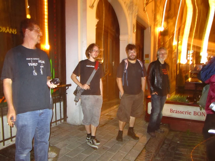 four guys standing by a building in front of their doors