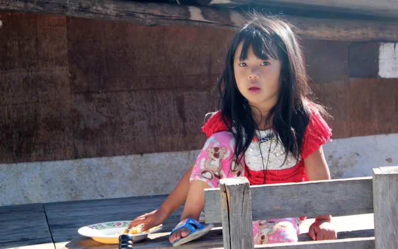 a little girl sitting by a table with plates