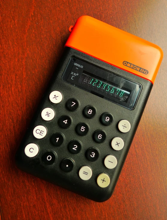 an orange and black calculator is on a wooden table