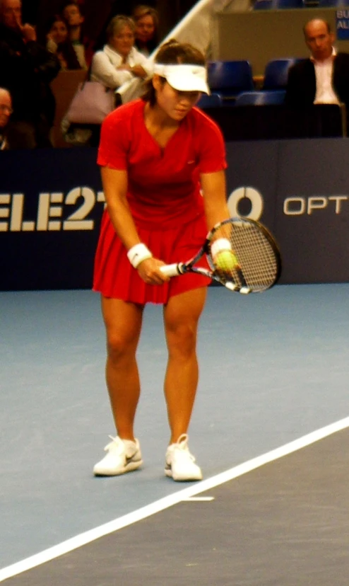 a woman in red dress holding a tennis racquet on court