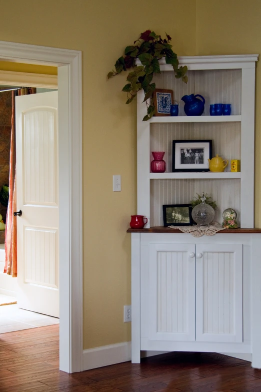 the corner of the room has a cabinet and wall unit