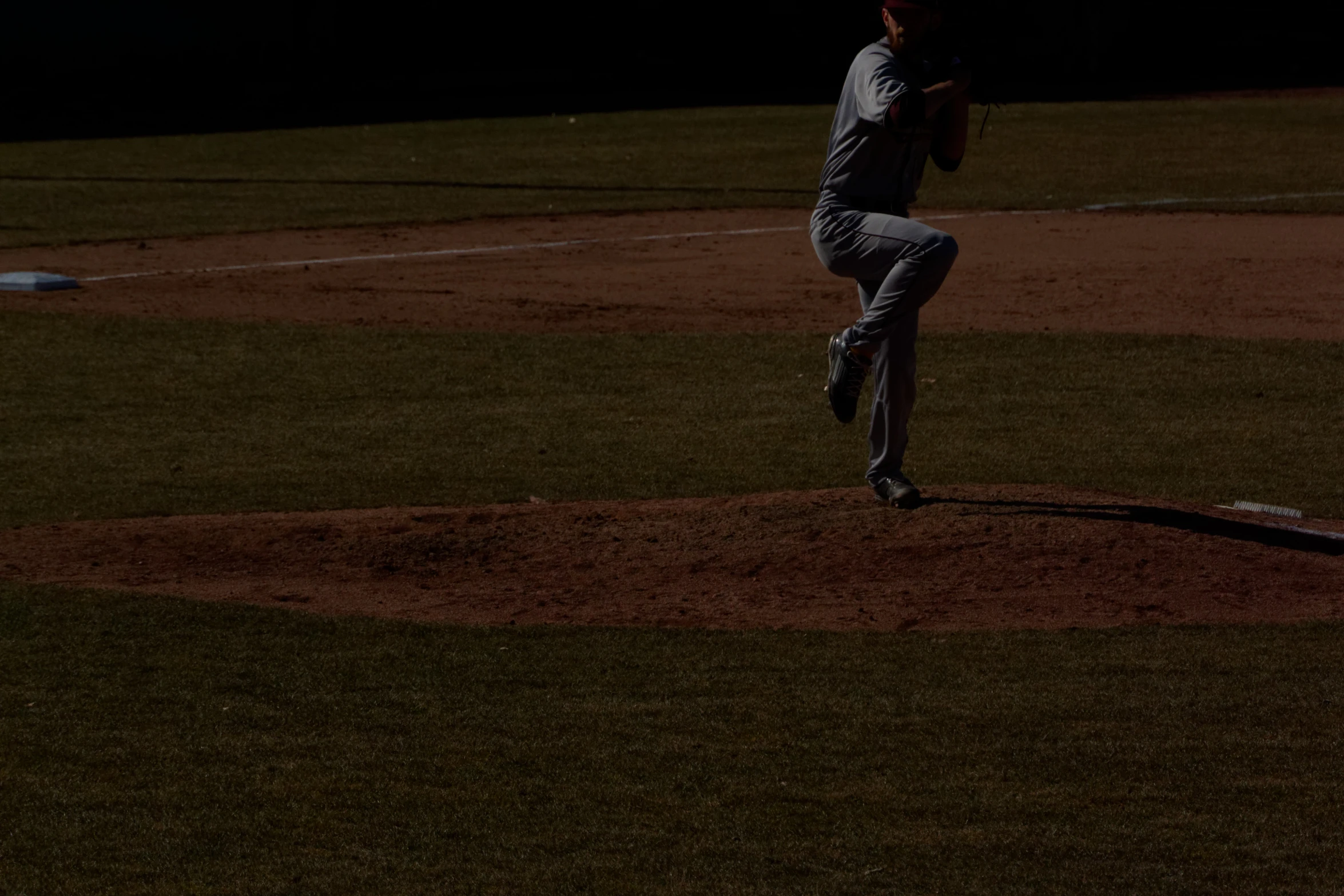 pitcher in motion during a baseball game in the dark