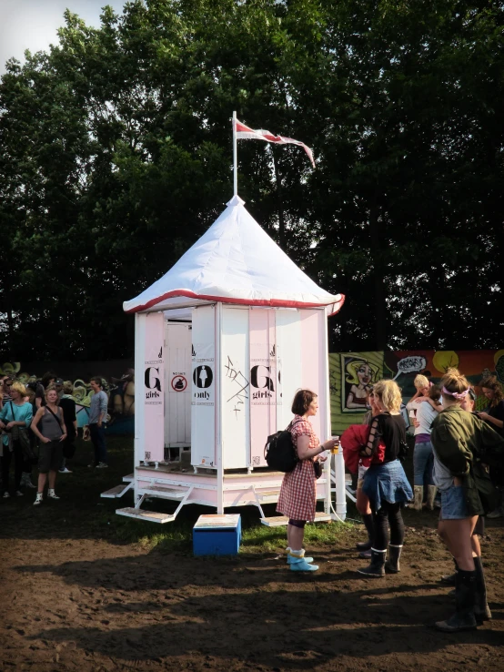 a group of people standing around a portable toilet