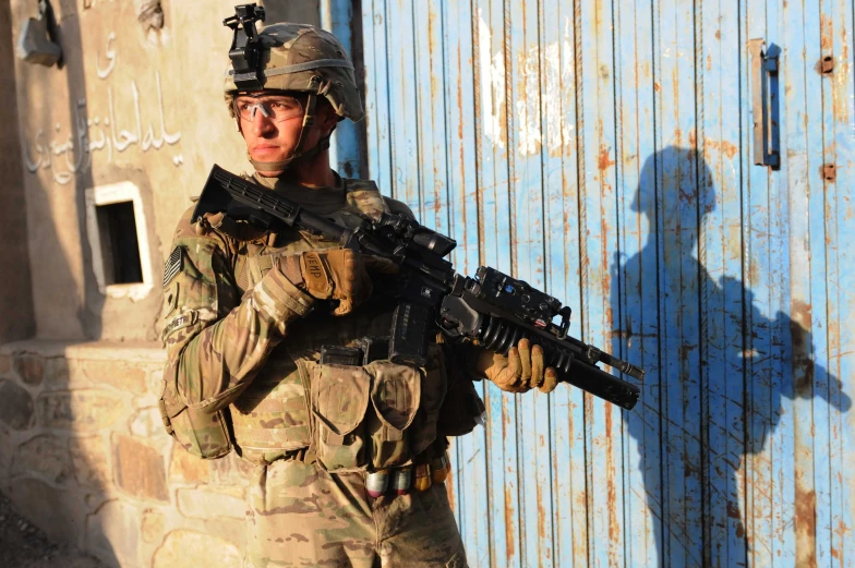 the soldier is holding a rifle outside near the door