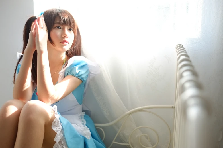 an asian girl in a blue dress is sitting down
