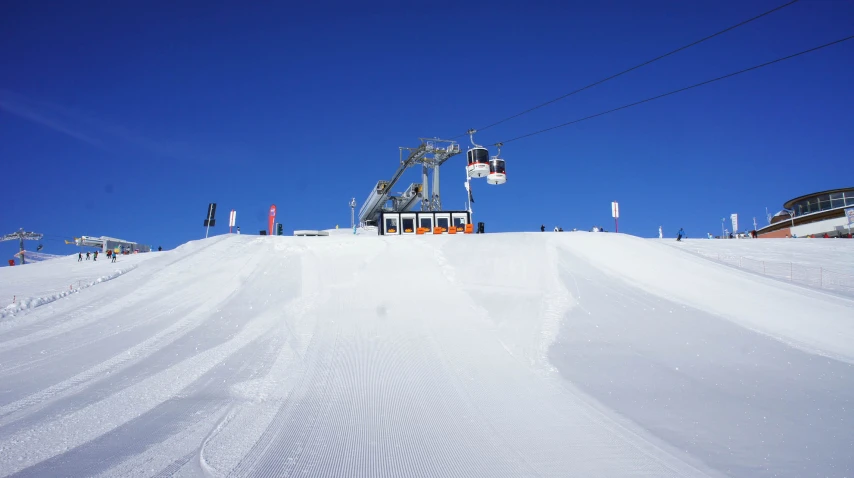 an orange lift sits atop the snow and has the sky in the background