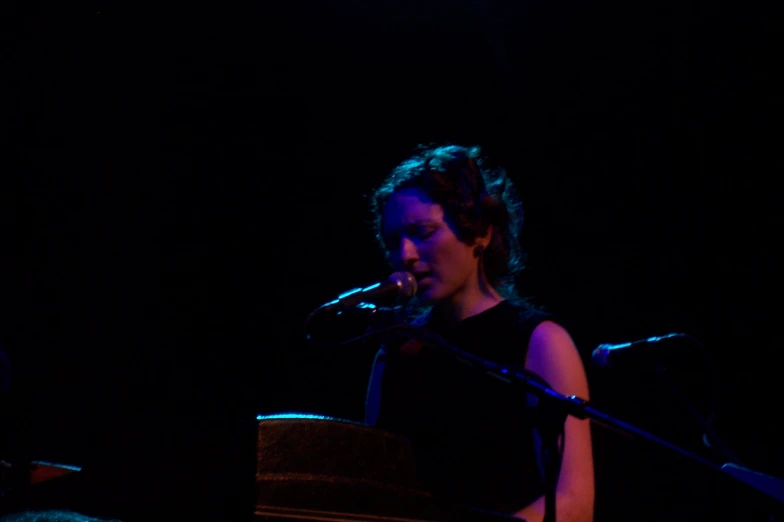 a woman singing into a microphone while playing the keyboard