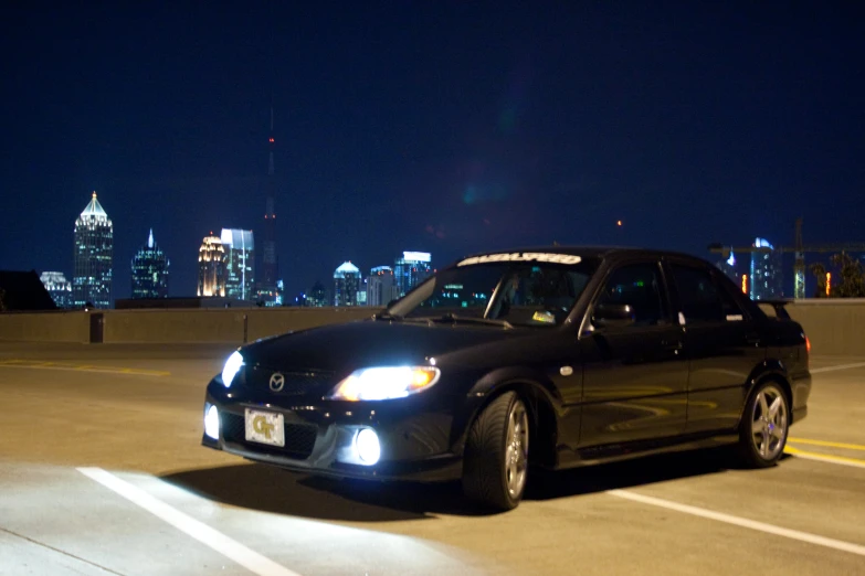 a small car driving in the dark with city lights