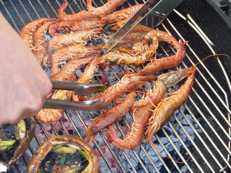 two tongs are being used to eat shrimp on the grill