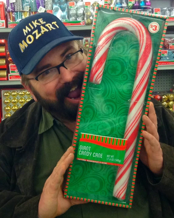 a man holding up a large candy cane