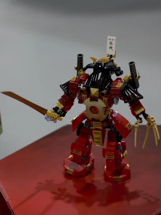 the red and gold robot is sitting on the table