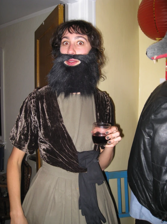 a man wearing a black beard and a dark suit has a funny expression on his face