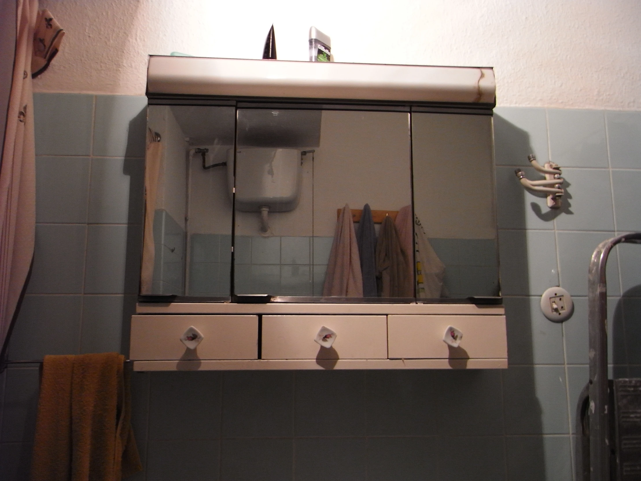 there is a small cabinet with mirrors in the bathroom