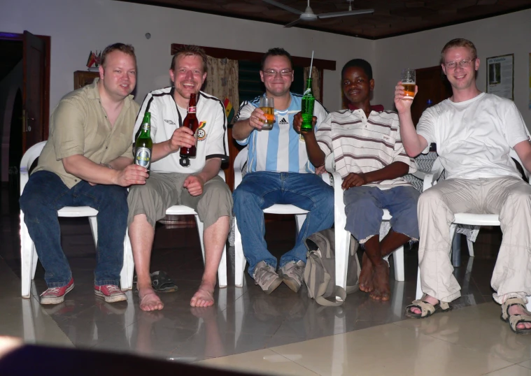 the men are holding different beers posing for a po