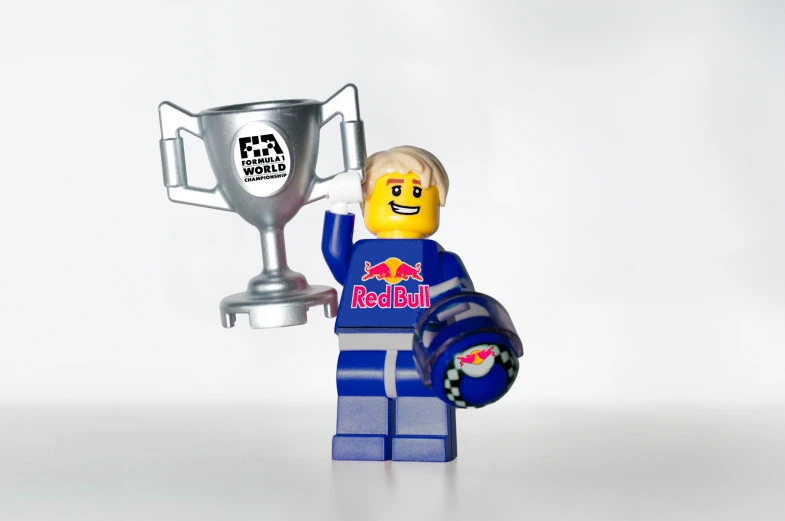 a lego figure holding up a silver trophy
