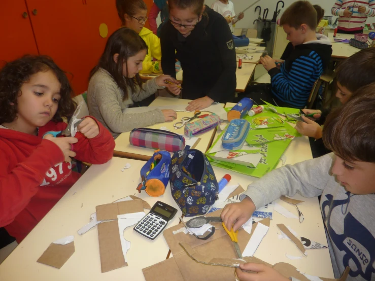 a group of children at a table using scissors and construction paper