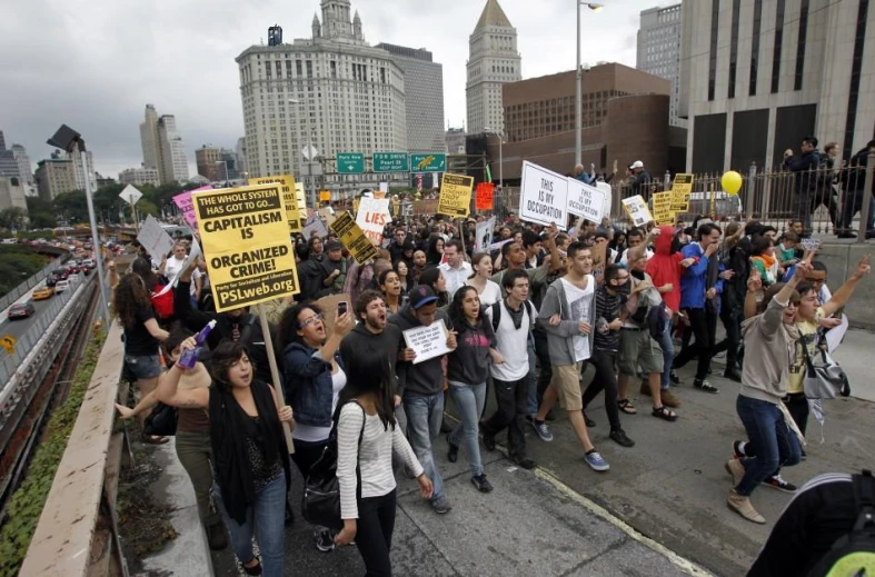 there are protestors marching down a street in front of a tall building