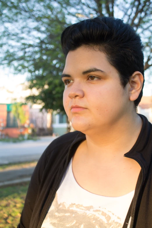 a close up of a person with a tree in the background