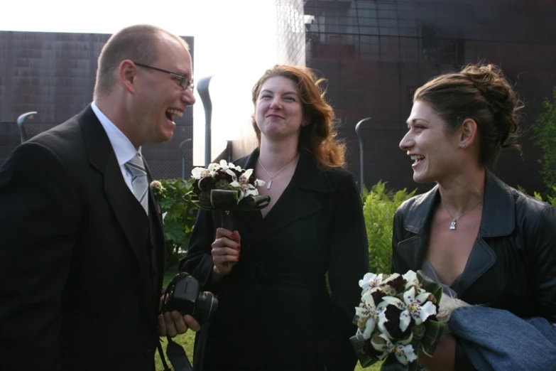 a man and two women who are holding flowers