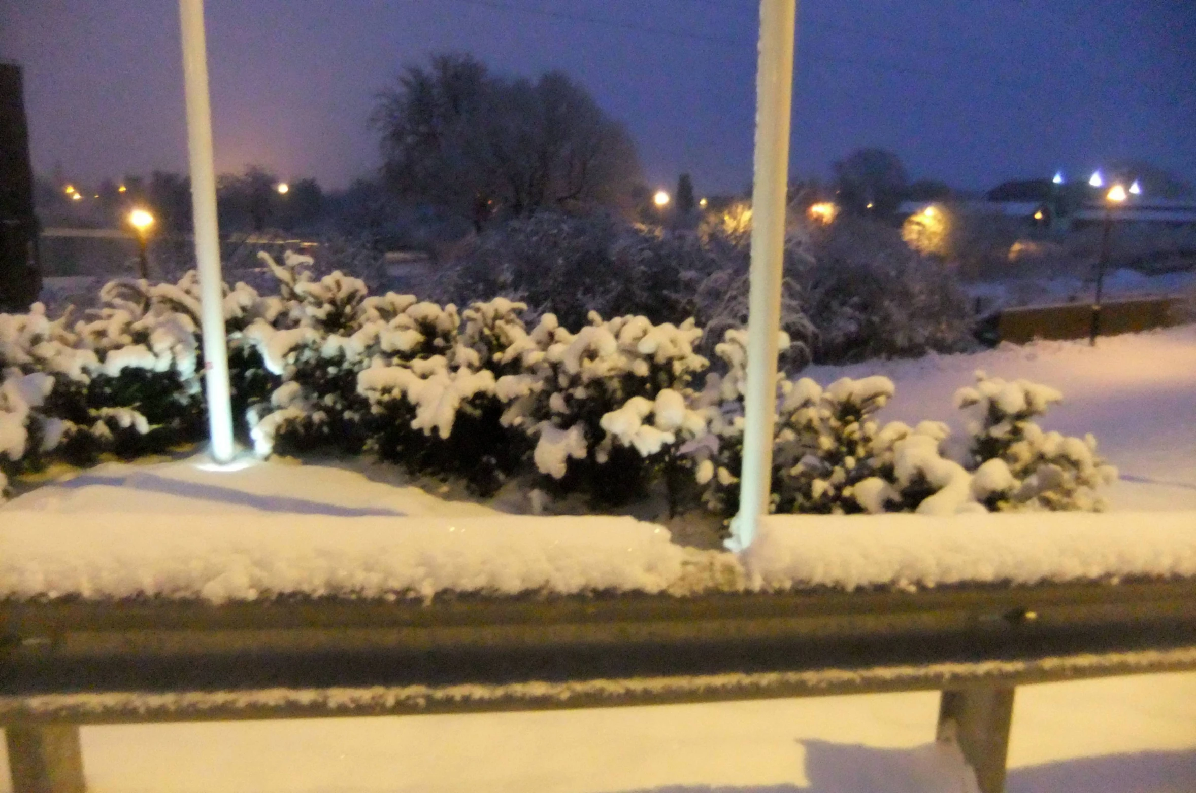 snow is covering a rail next to a park bench