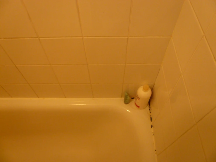 a bathroom with white tile on the floor and a single roll of toilet paper on the tub