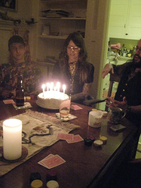 a group of people around a cake with lit candles