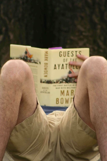 a man is laying down reading a book