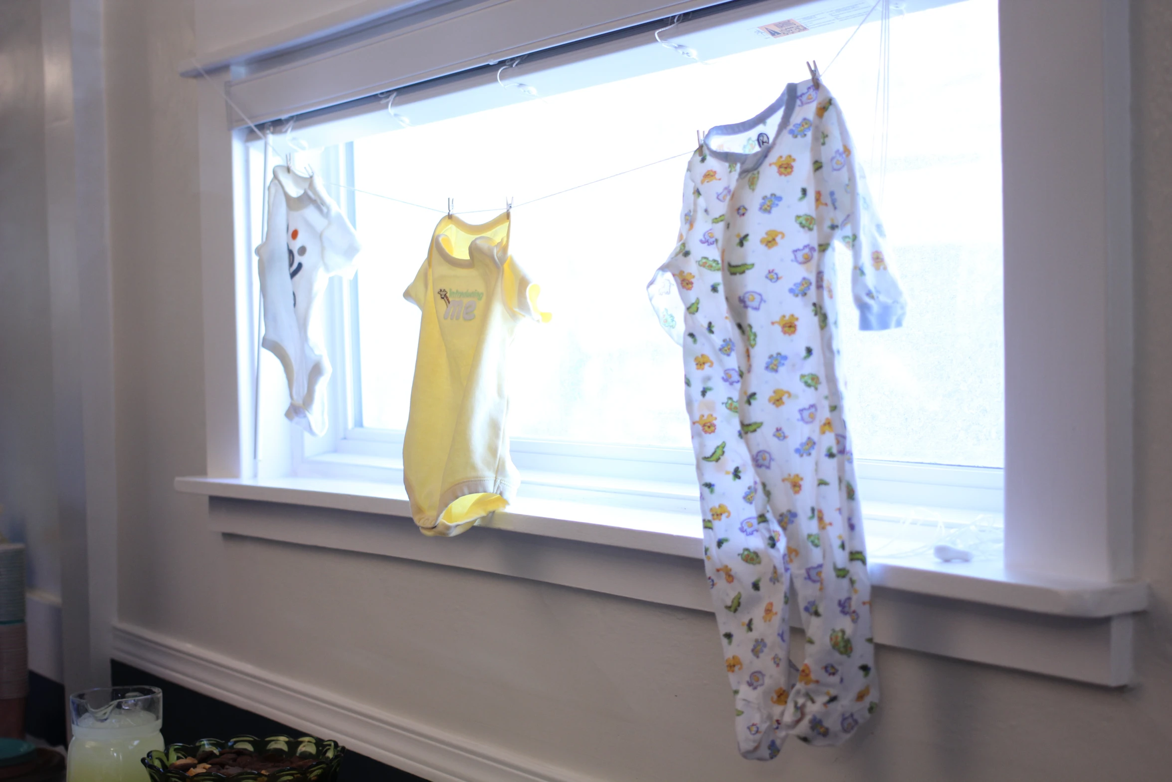 some pajamas hang from the windowsill on a sunny day