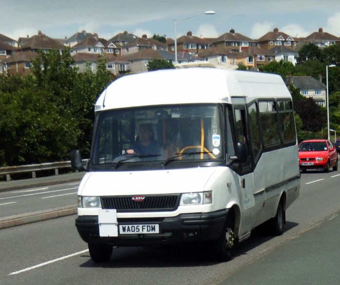 a van drives on the side of the road next to a small truck