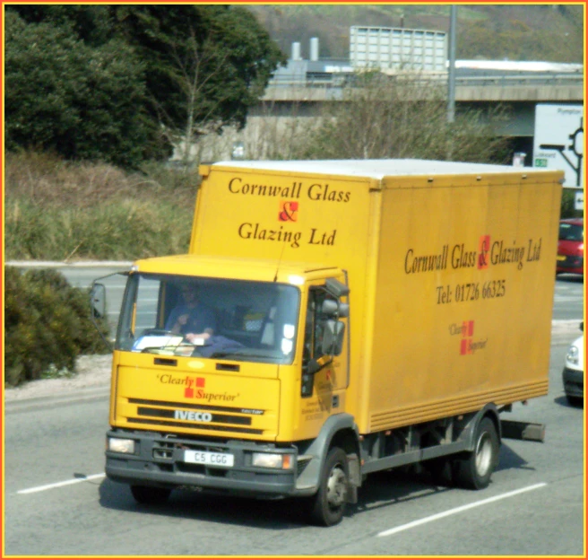 a yellow utility truck driving down a road