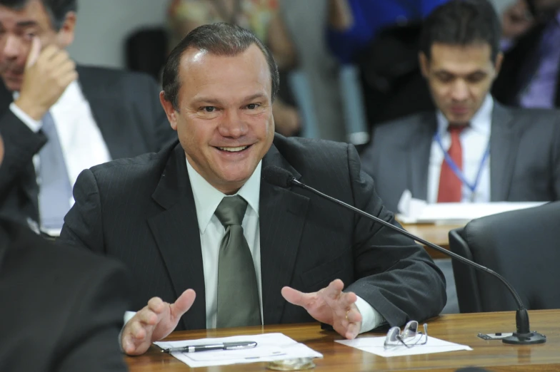 a man wearing a suit and tie sitting at a table