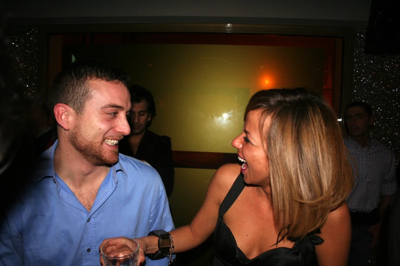 a man and woman in dress clothes having drinks