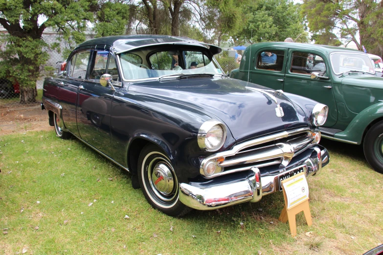 classic car displayed in grassy area during outdoor event