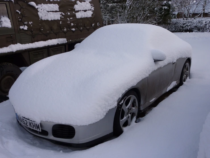 a car covered in snow with trees behind it