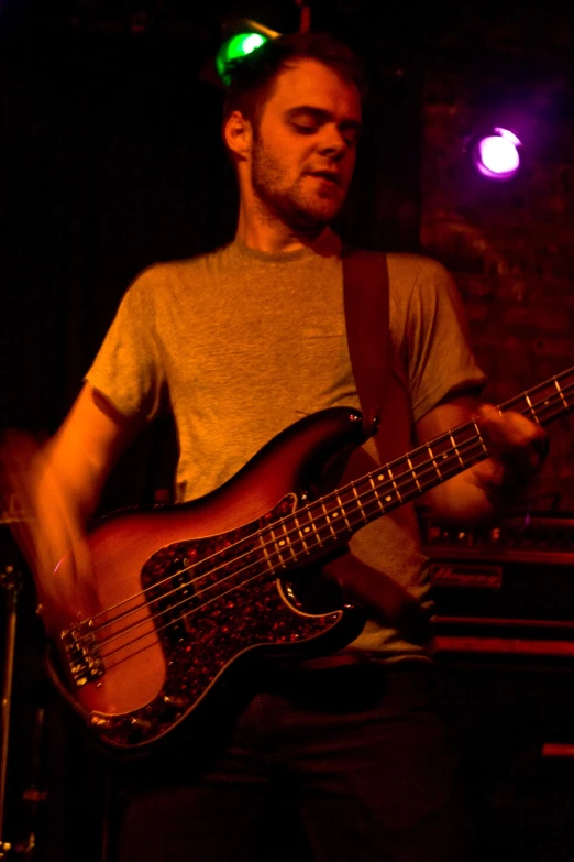 a man in grey shirt playing an electric guitar