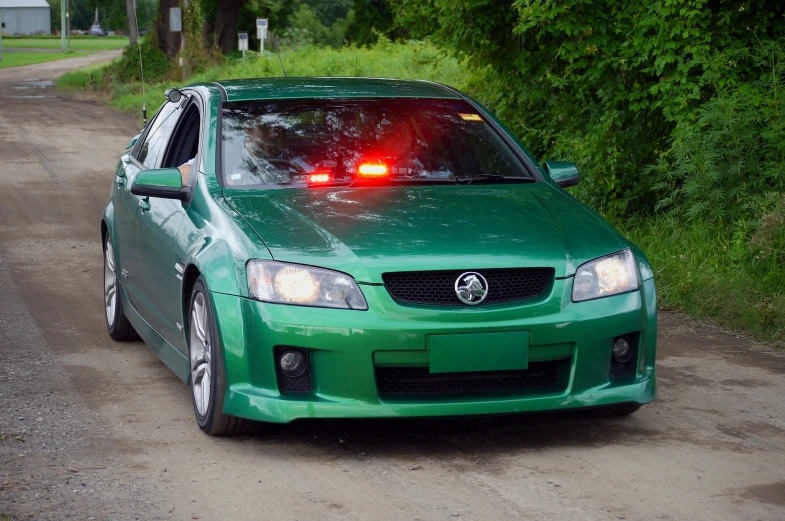 a green car with bright red ke lights on the back
