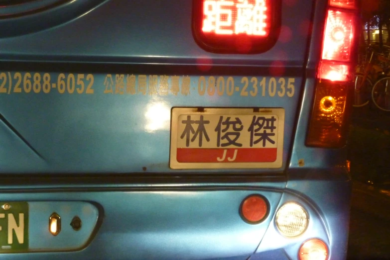 a blue taxi with chinese letters and a stop light