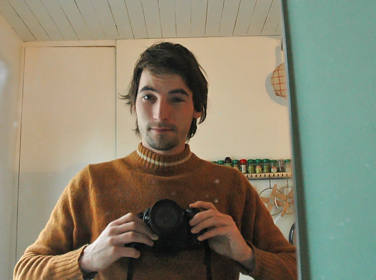 a man with long hair is standing in front of the mirror taking a picture