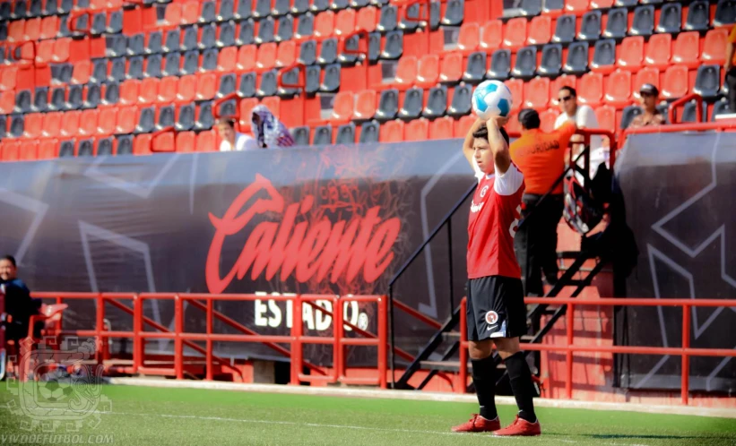 a man holds a soccer ball near an empty stadium