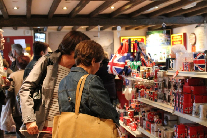 people are standing in a store near shelves with various items