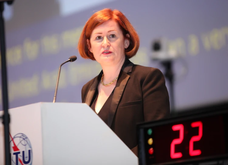 a red headed woman at a podium speaking on the topic of climate change