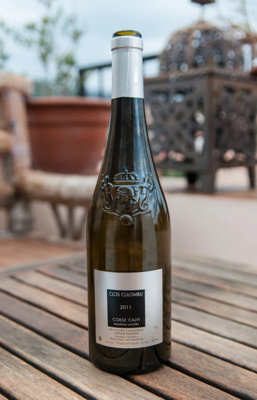 an empty wine bottle on a table in the sun