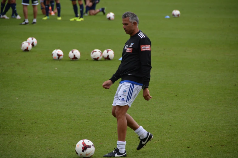 a man in black shirt and white shorts playing with soccer balls