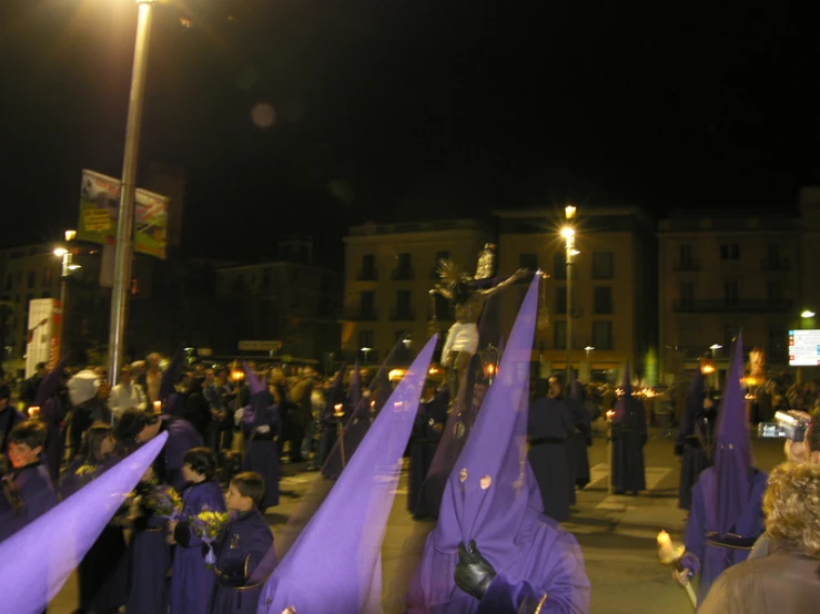 a crowd of people wearing purple dresses stand around a statue