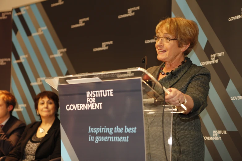 two women are sitting at a podium while two others look on